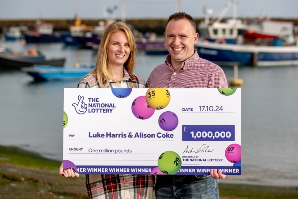 a man and a woman holding a cheque from the national lottery