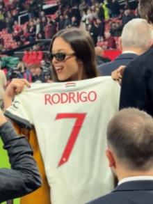 a woman holds up a jersey with the name rodrigo on it