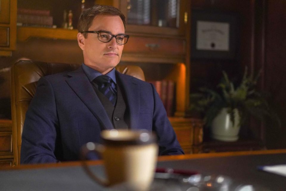 a man in a suit and tie sits at a desk