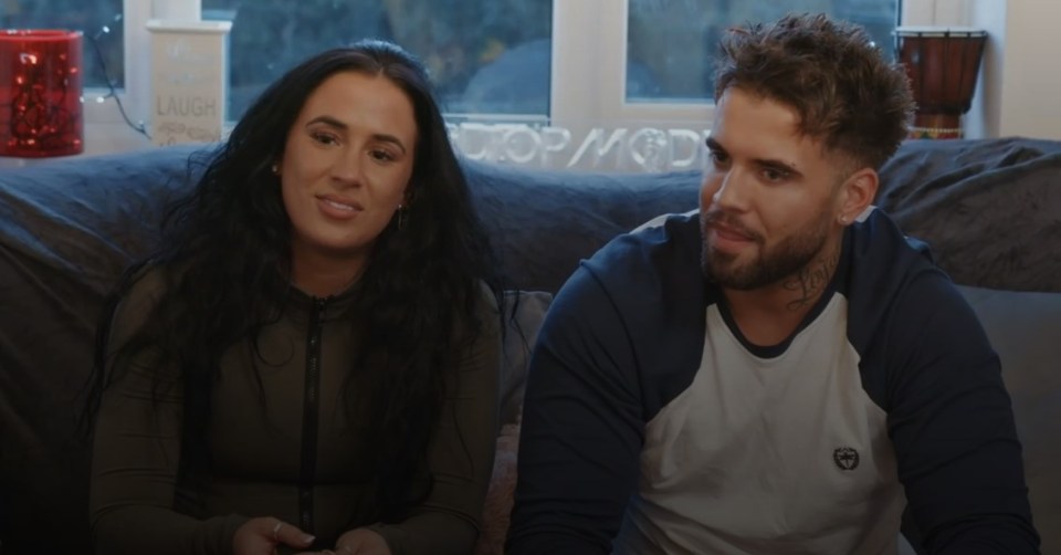 a man and a woman sit on a couch in front of a sign that says laugh