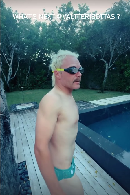 a shirtless man wearing swim trunks and goggles stands next to a pool