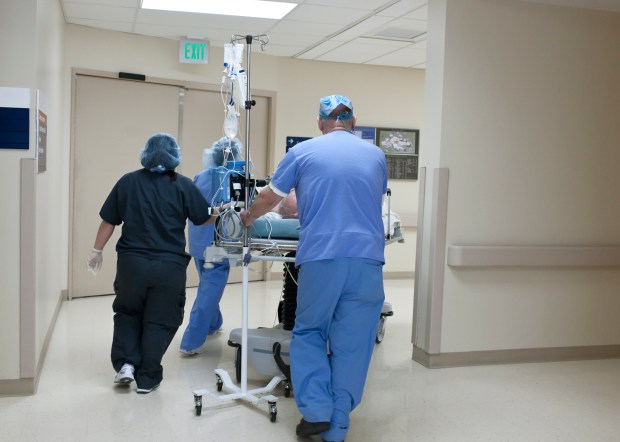 a green exit sign hangs above a hospital hallway