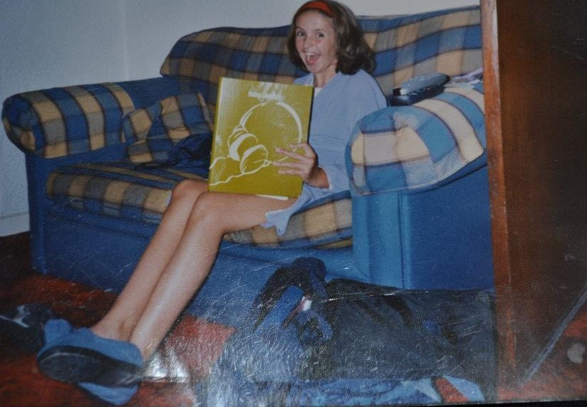 a woman is sitting on a couch holding a book titled headphones