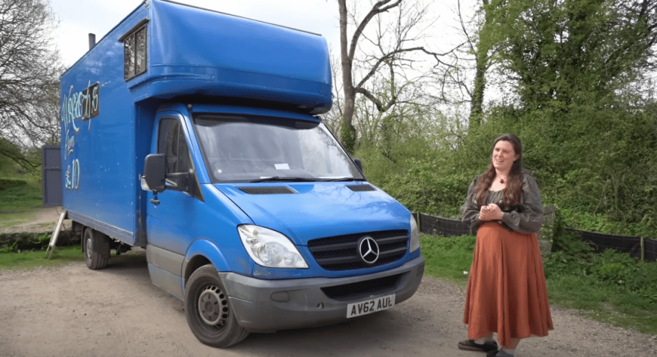 a woman stands in front of a blue mercedes van