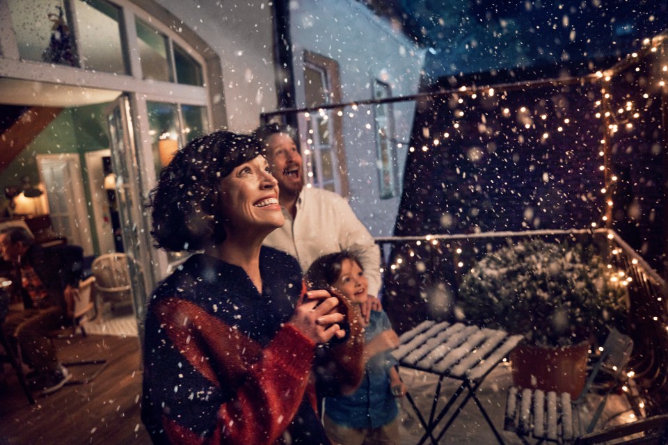 a family standing on a balcony watching snow fall