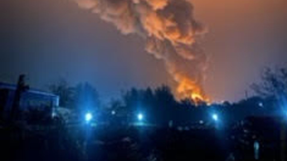 a large cloud of smoke is coming out of a building at night .