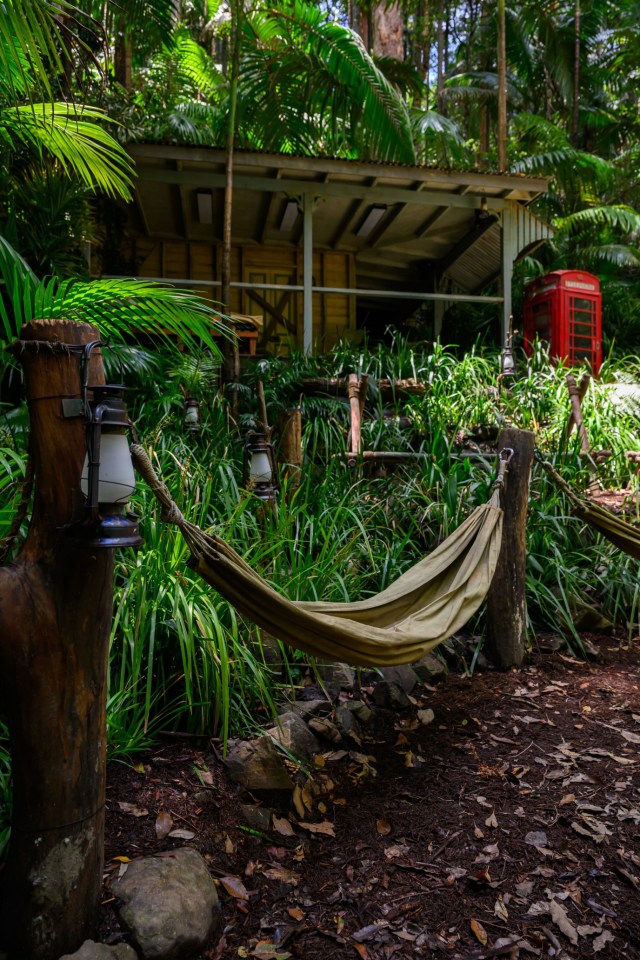 a hammock is sitting in front of a red telephone booth