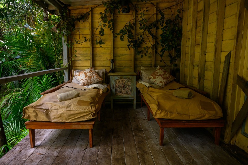 two beds on a porch with a nightstand in the background