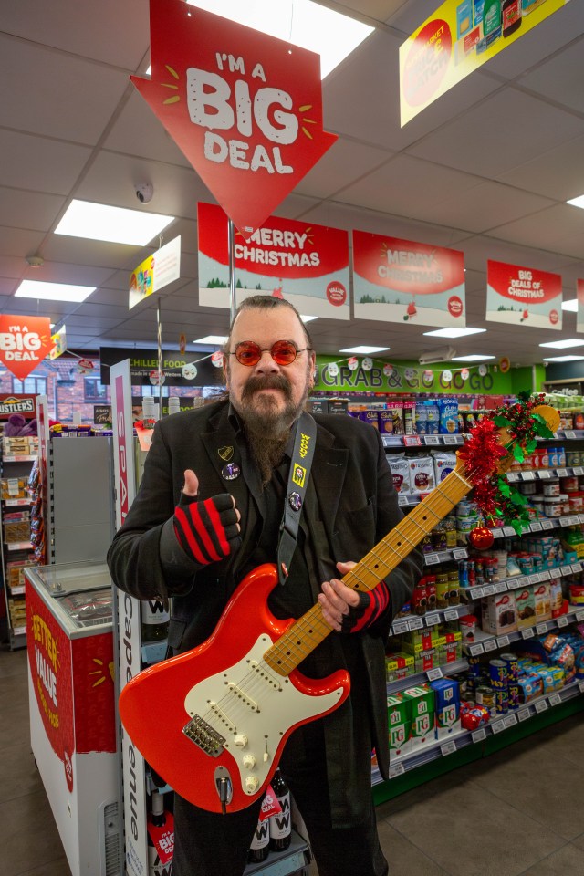 a man holding a red guitar in front of a sign that says i 'm a big deal