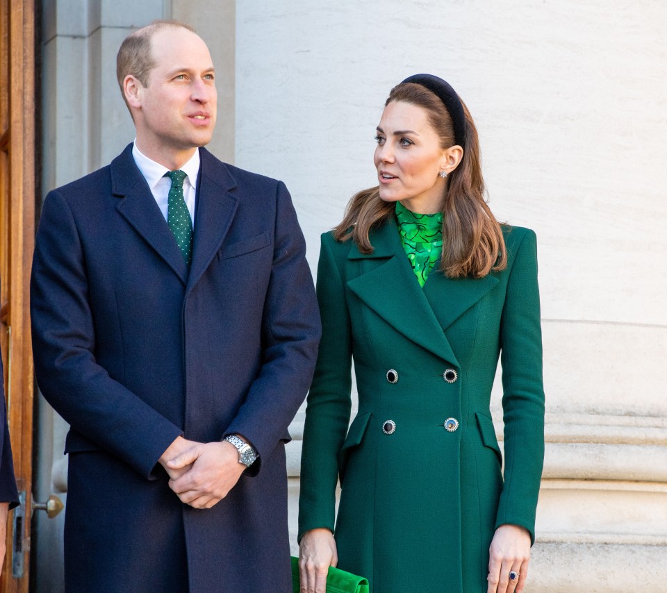 a man in a suit and tie and a woman in a green coat stand next to each other