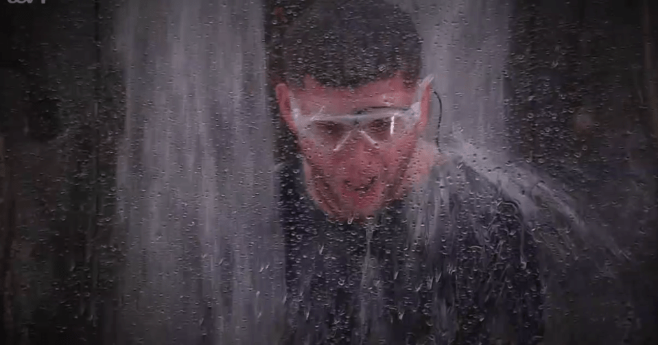 a man wearing goggles is standing in front of a waterfall