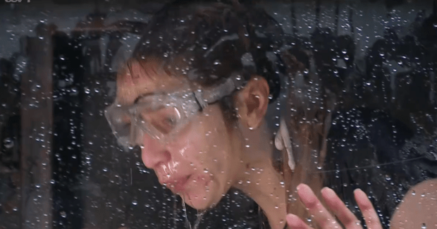 a woman wearing goggles is behind a window with water drops on it