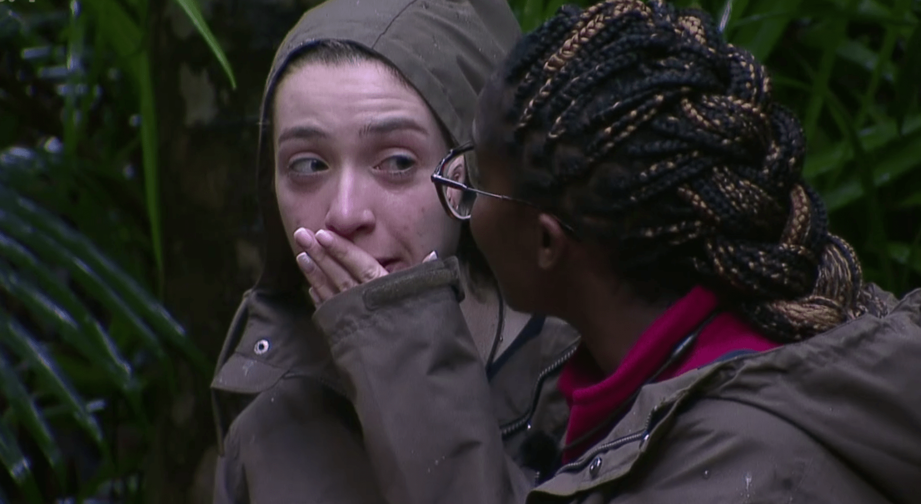 a woman with braids is covering her mouth with her hand