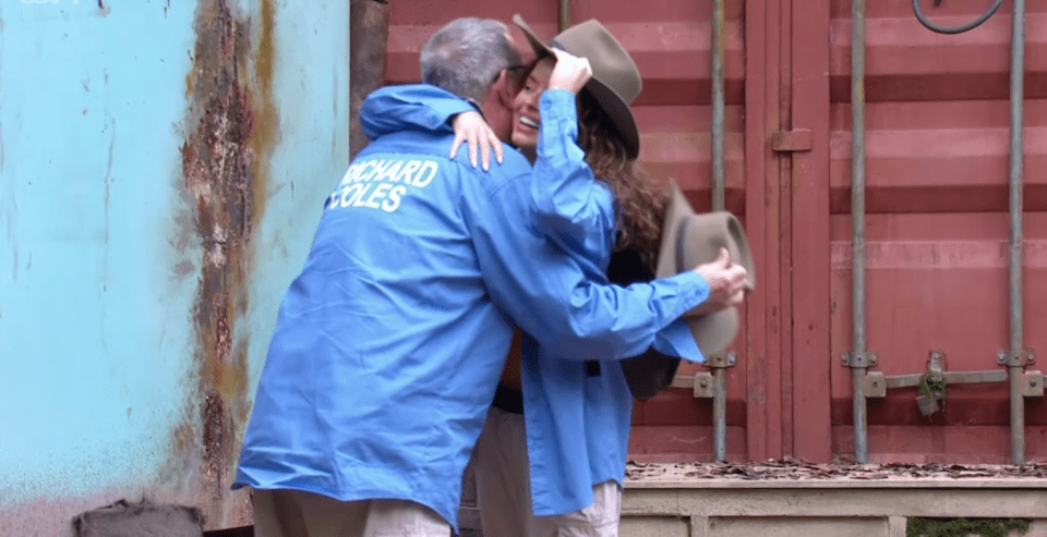 a man in a blue jacket that says richard coles is hugging a woman