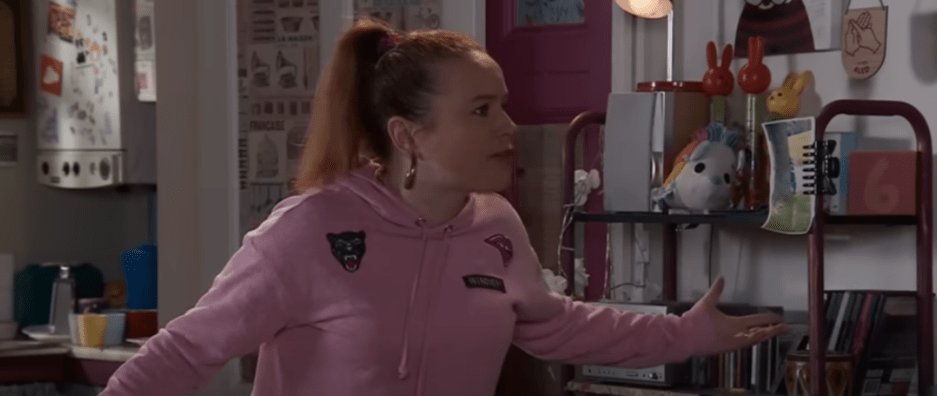 a woman wearing a pink sweatshirt with a patch that says ' i love you ' on it