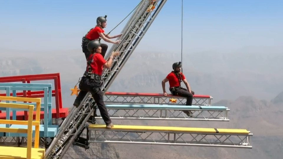 a man in a red shirt with the letter e on it climbs a ladder