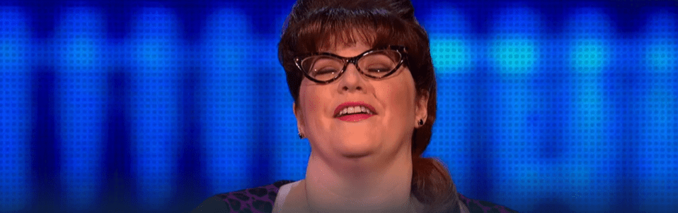 a woman wearing glasses is smiling in front of a blue background