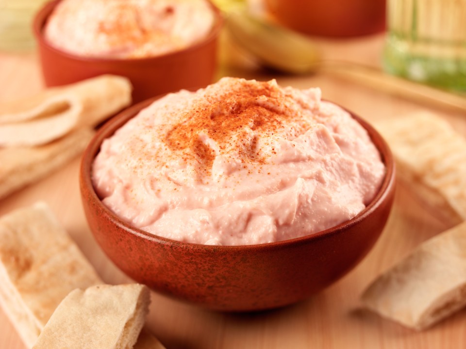 a bowl of dip is surrounded by pita bread