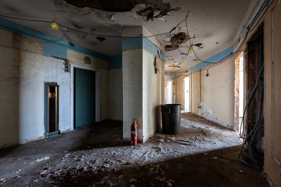 a red fire extinguisher sits on the floor of an abandoned building