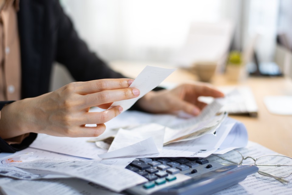 Woman reviewing receipts and using a calculator to calculate expenses.