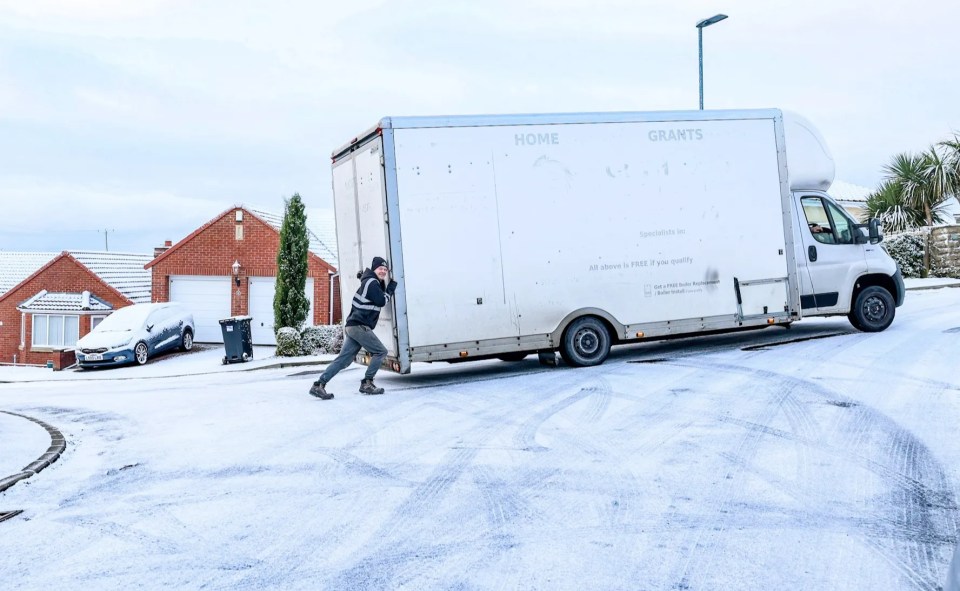 a man pushes a white van up a snow covered hill