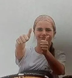 a young girl is giving a thumbs up while riding a roller coaster .