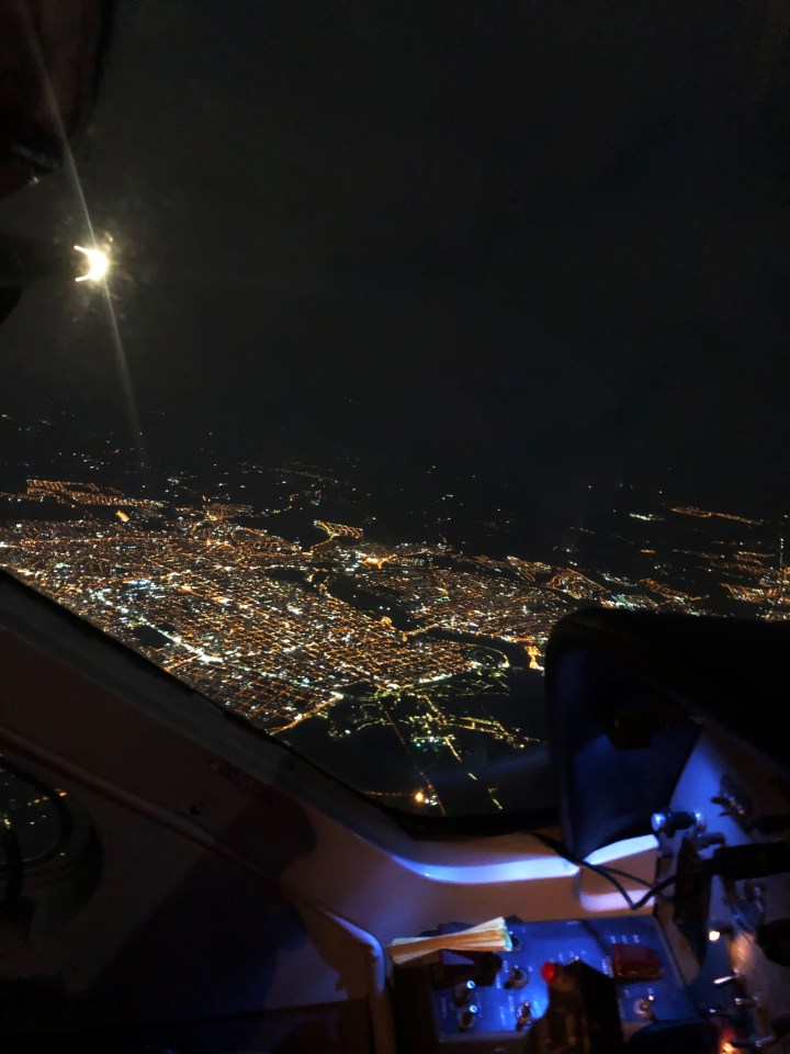 a view of a city at night from the cockpit of an airplane