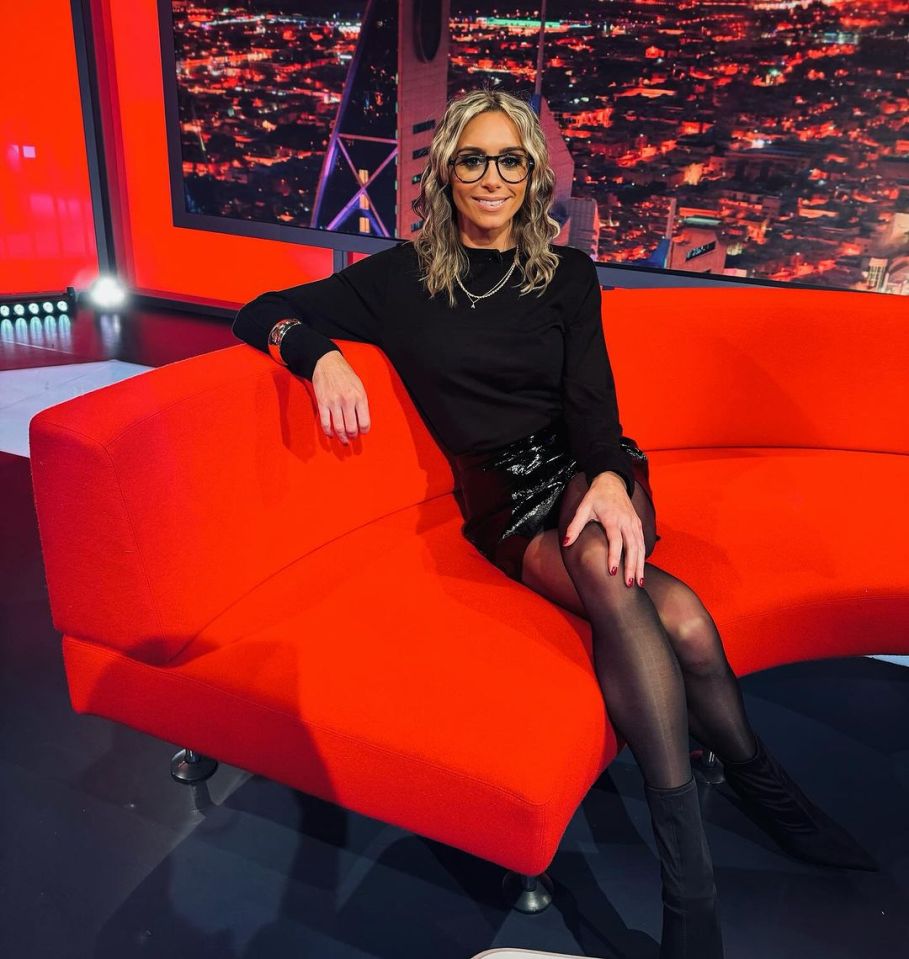 a woman wearing glasses sits on a red couch