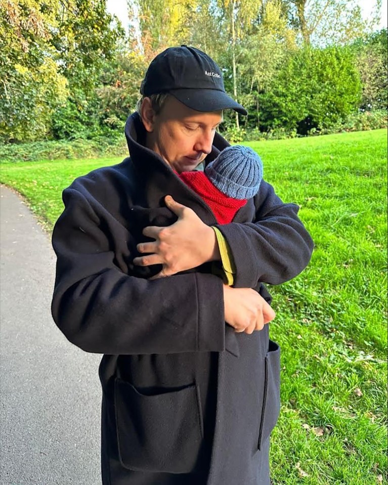 a man holding a baby wearing a hat that says ' abercrombie & fitch ' on it