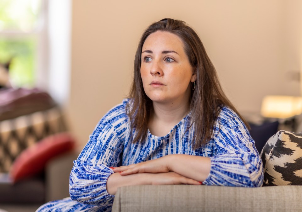 a woman in a blue and white tie dye shirt sits on a couch