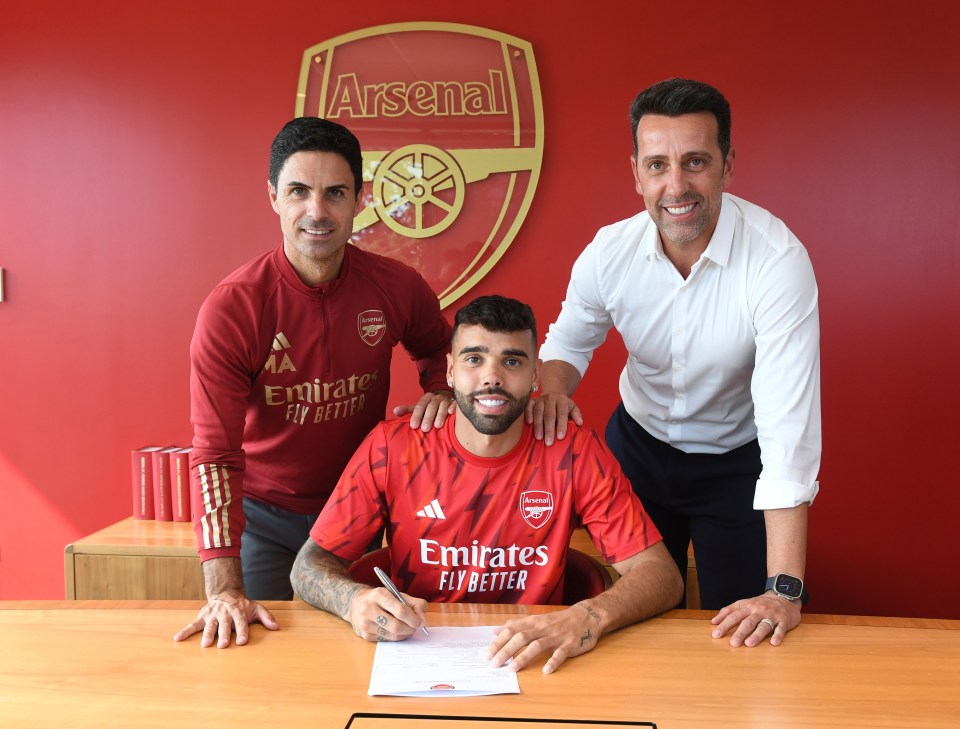 a man in a red emirates fly better shirt is signing a contract