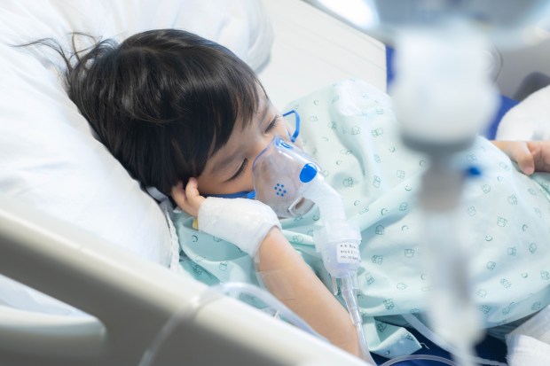 a child in a hospital bed with an oxygen mask on