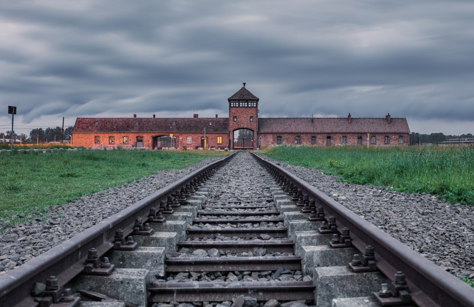 train tracks leading to a brick building with a tower