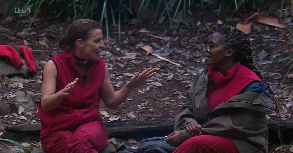 two women are sitting on a log in the woods with itv 1 behind them