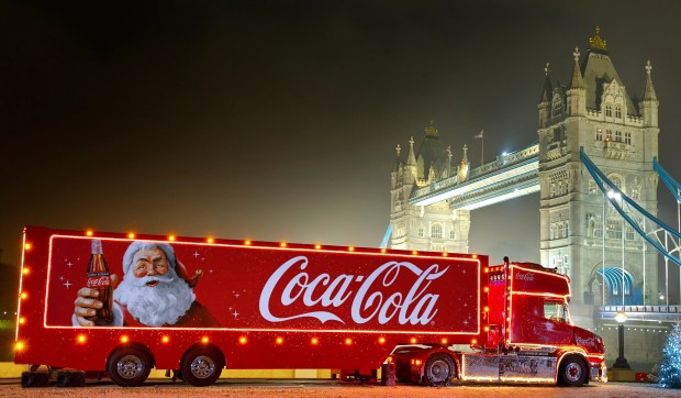 a coca cola truck with santa on the side is parked in front of a bridge