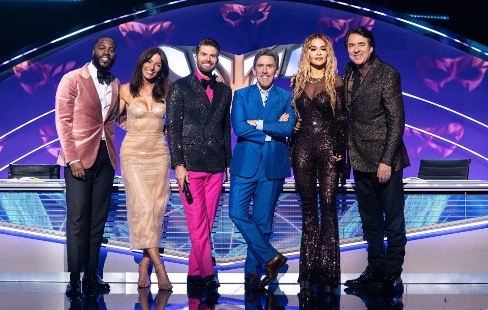 a group of people posing for a picture with one woman in a pink dress