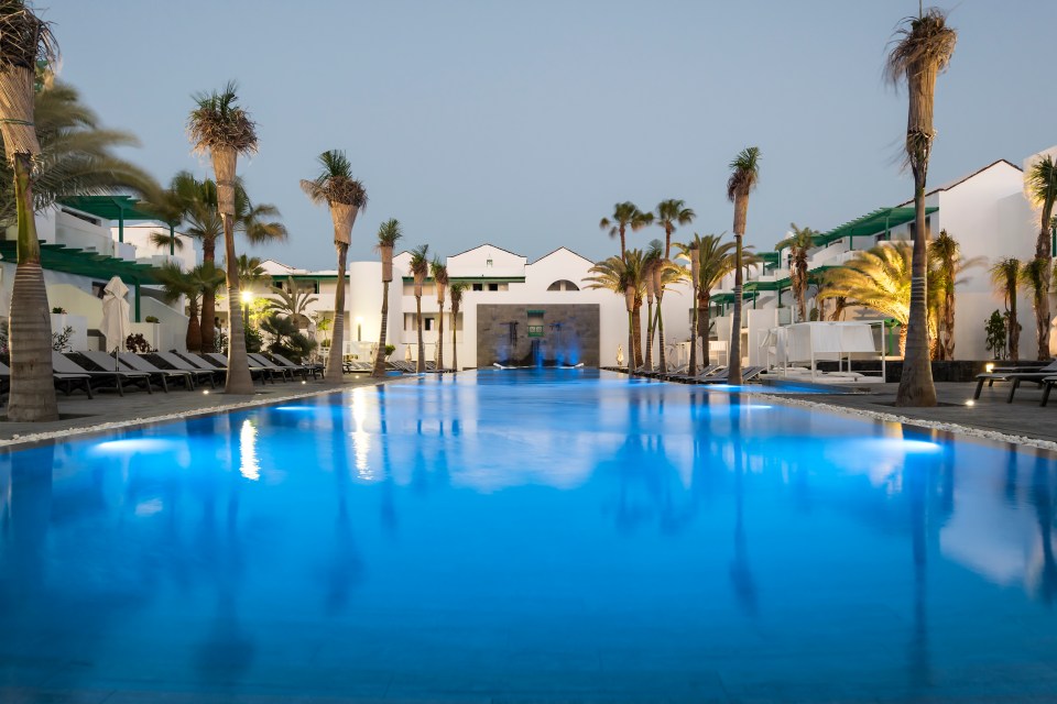 A lovely courtyard main pool lined with palm trees with plenty of sun loungers