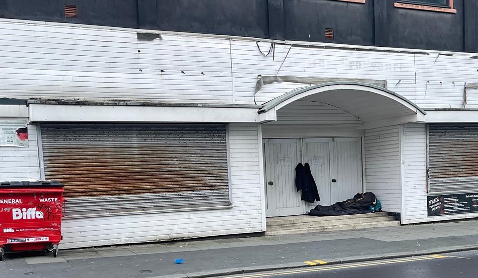 One homeless person sleeps in a shopfront door way