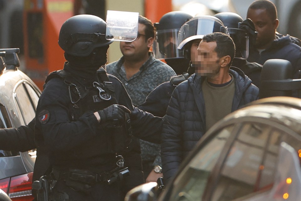 A hostage is accompanied by a police officer after being released from the restaurant