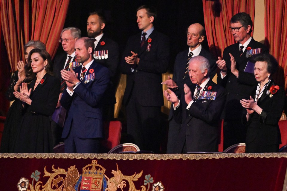 a group of people applauding in front of a coat of arms