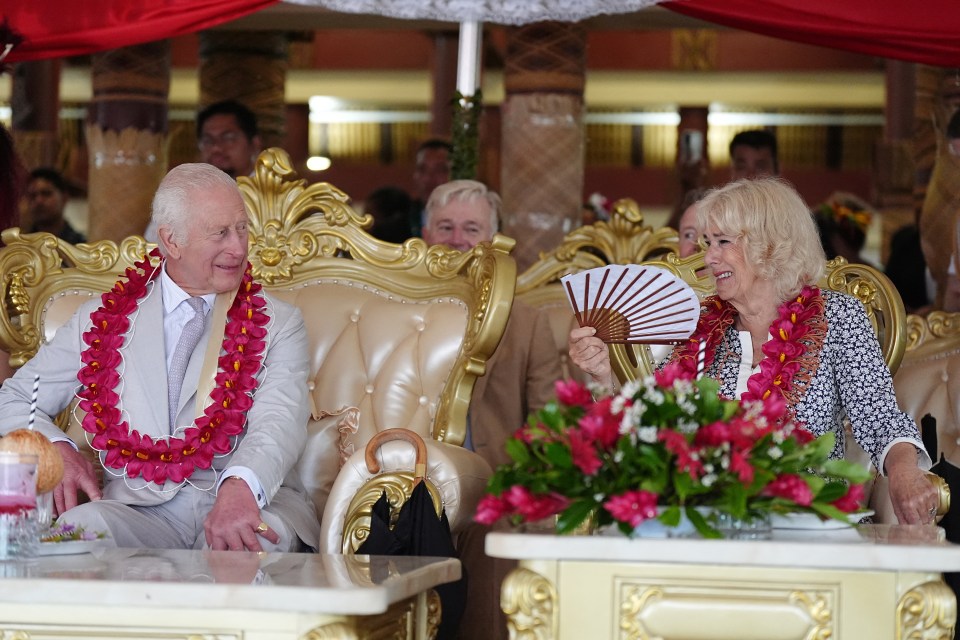 a man and woman are sitting at a table with flowers and a fan