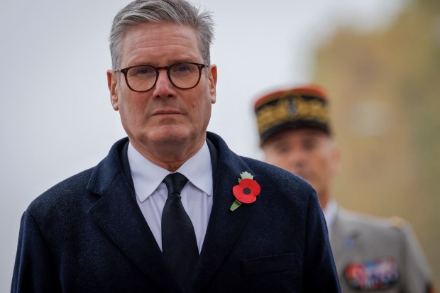 a man with glasses and a poppy pin on his jacket