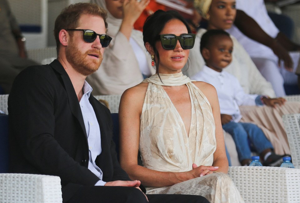 a man and a woman wearing sunglasses sit in a stadium