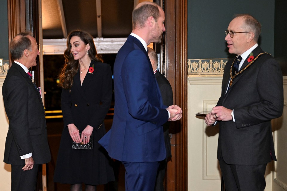 a man in a black tie has a poppy on his lapel