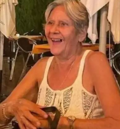 an elderly woman is smiling while sitting at a table in a restaurant .