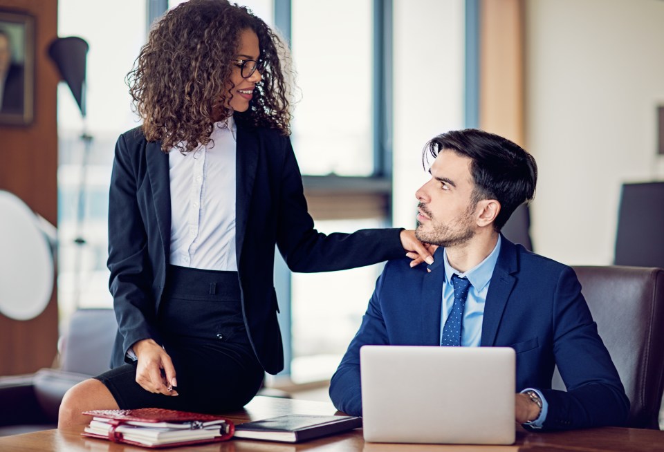 a woman standing next to a man in front of a laptop