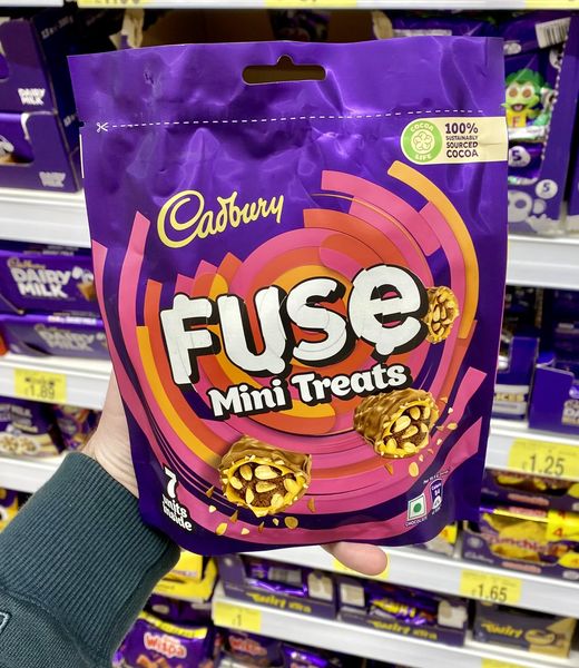 a person is holding a bag of cadbury fuse mini treats