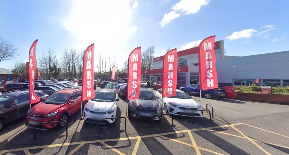 a row of cars are parked in front of a marsh car dealership