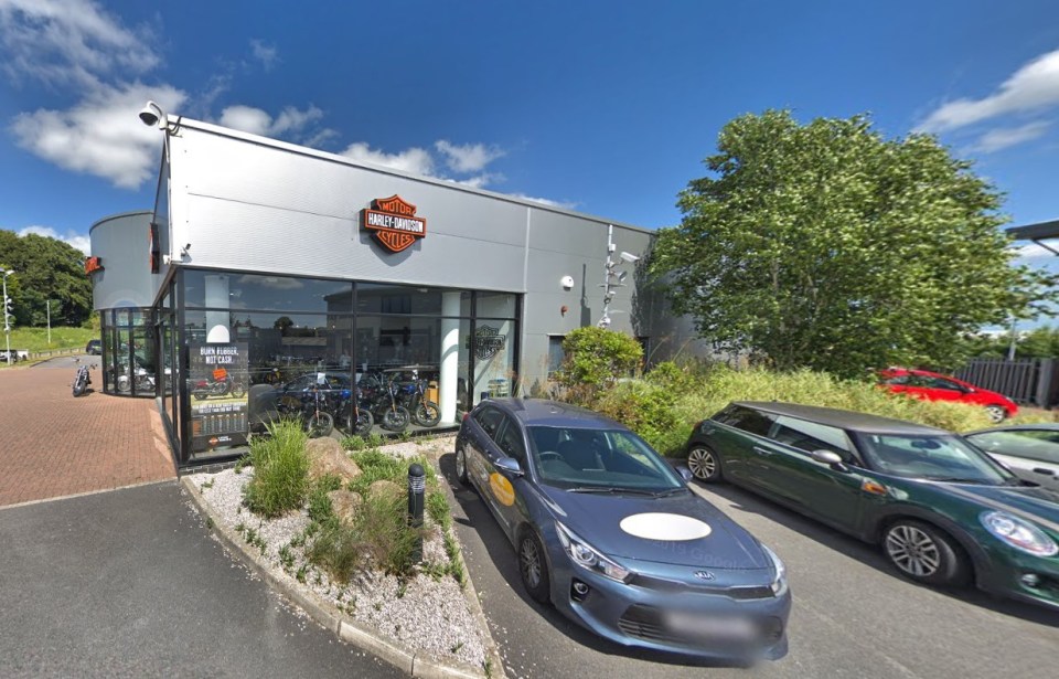 a harley davidson dealership with cars parked outside