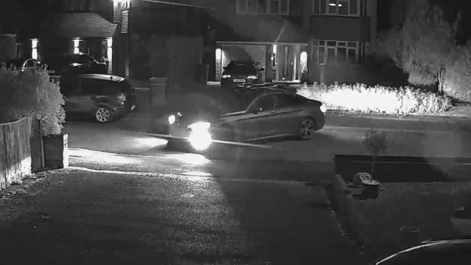 a black and white photo of a car driving down a street